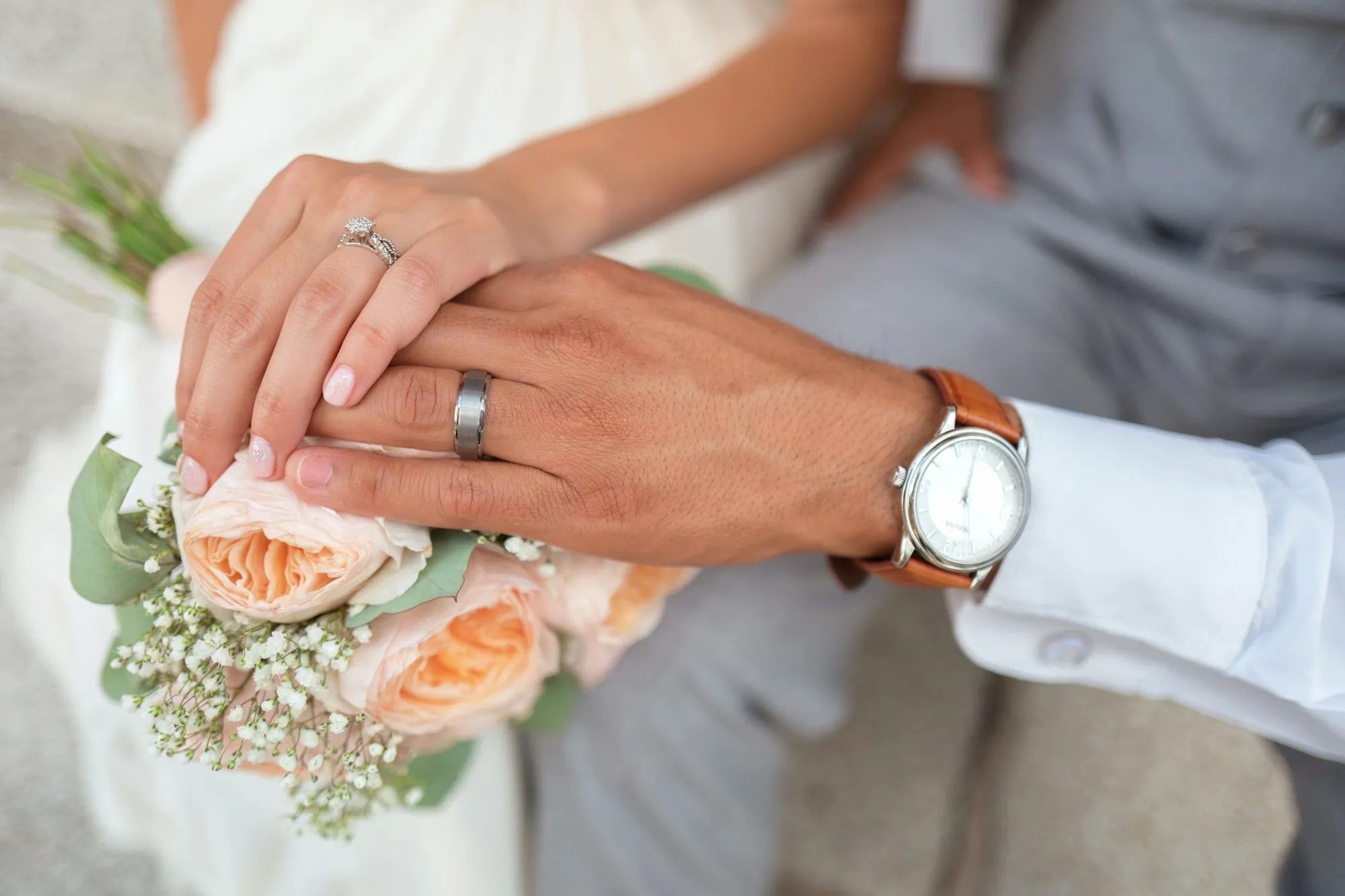 A couple's hands with wedding rings and a bouquet